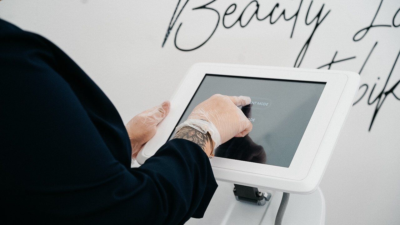 Eine Person benutzt ein Tablet , auf dem an der Wand hinter ihr das Wort „ Schönheit “ steht.