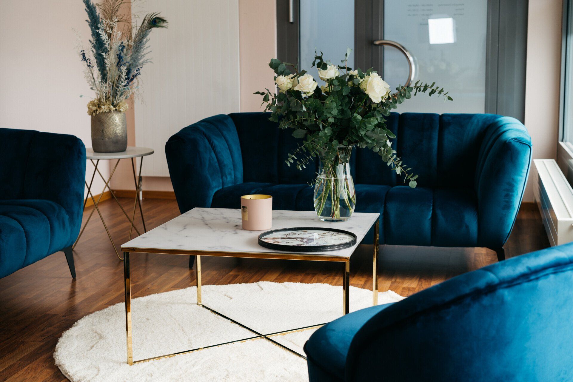 Ein Wohnzimmer mit zwei blauen Sofas und einem Couchtisch mit einer Blumenvase darauf.