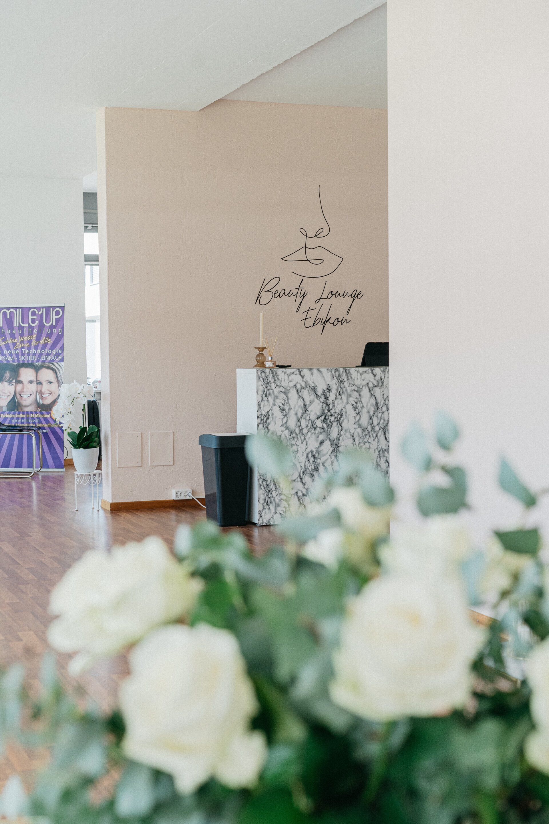 Ein Raum mit einem Schild an der Wand und Blumen im Vordergrund.