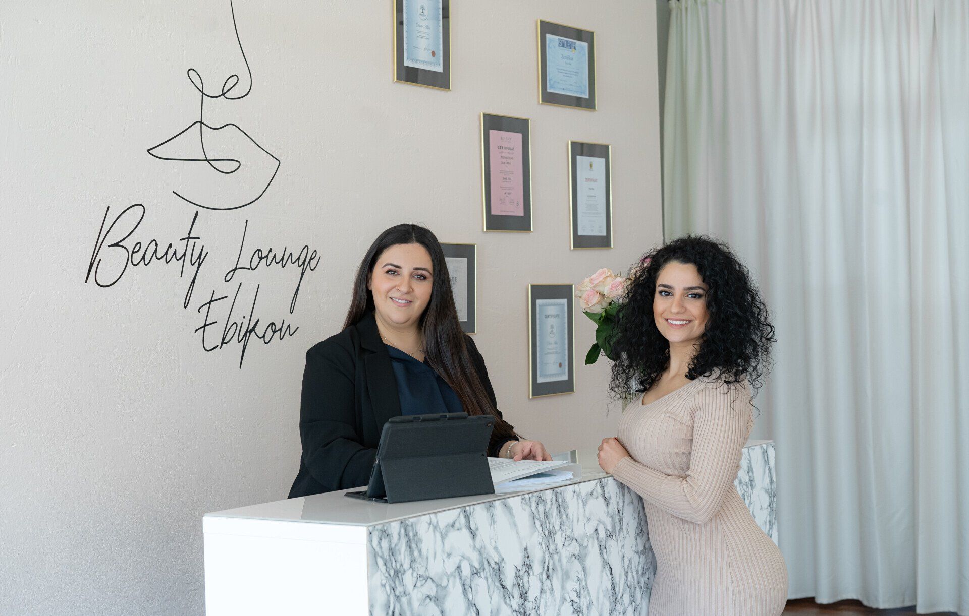 Zwei Frauen stehen an einem Tresen in einem Schönheitssalon.