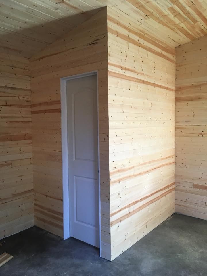 A plain white door set into an interior corner featuring walls and a ceiling finished with light-colored horizontal wood.