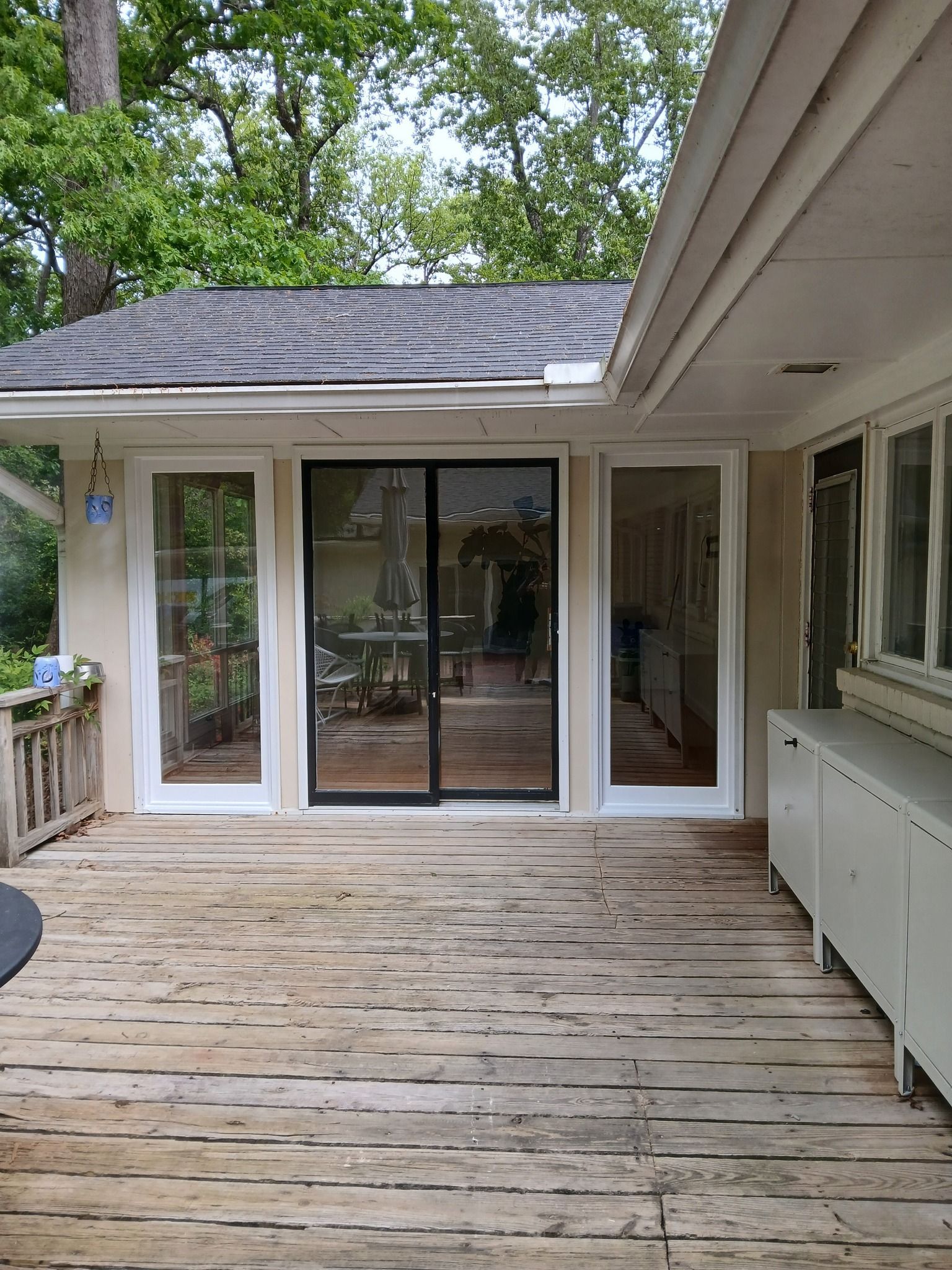 Back deck with a sliding glass door and windows; wood deck is weathered.