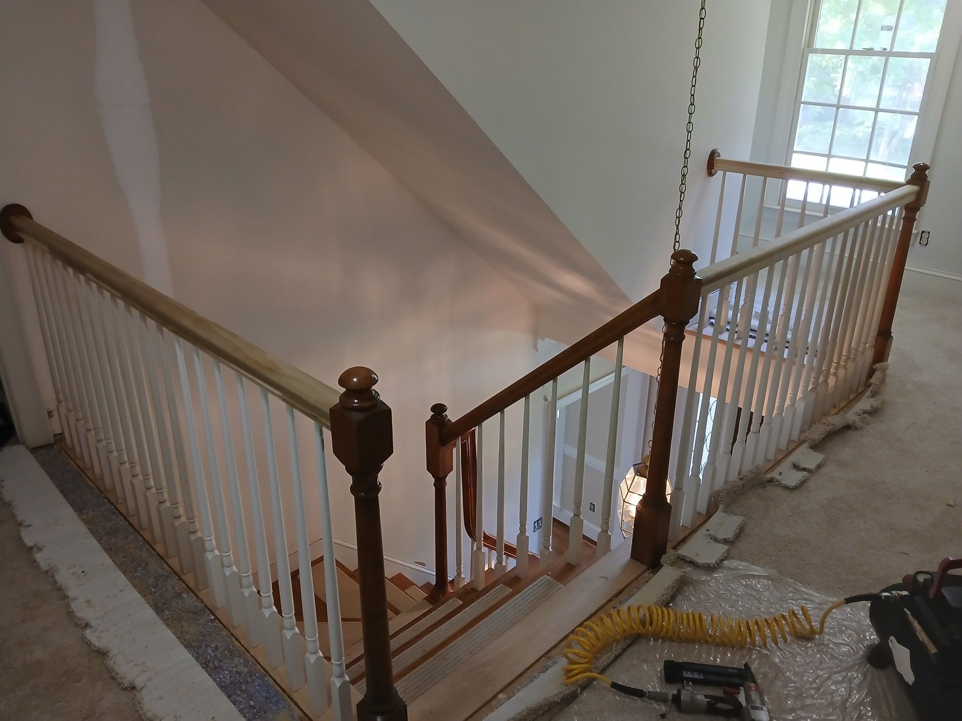 Staircase with white balusters and wooden handrails, leading down from a landing.