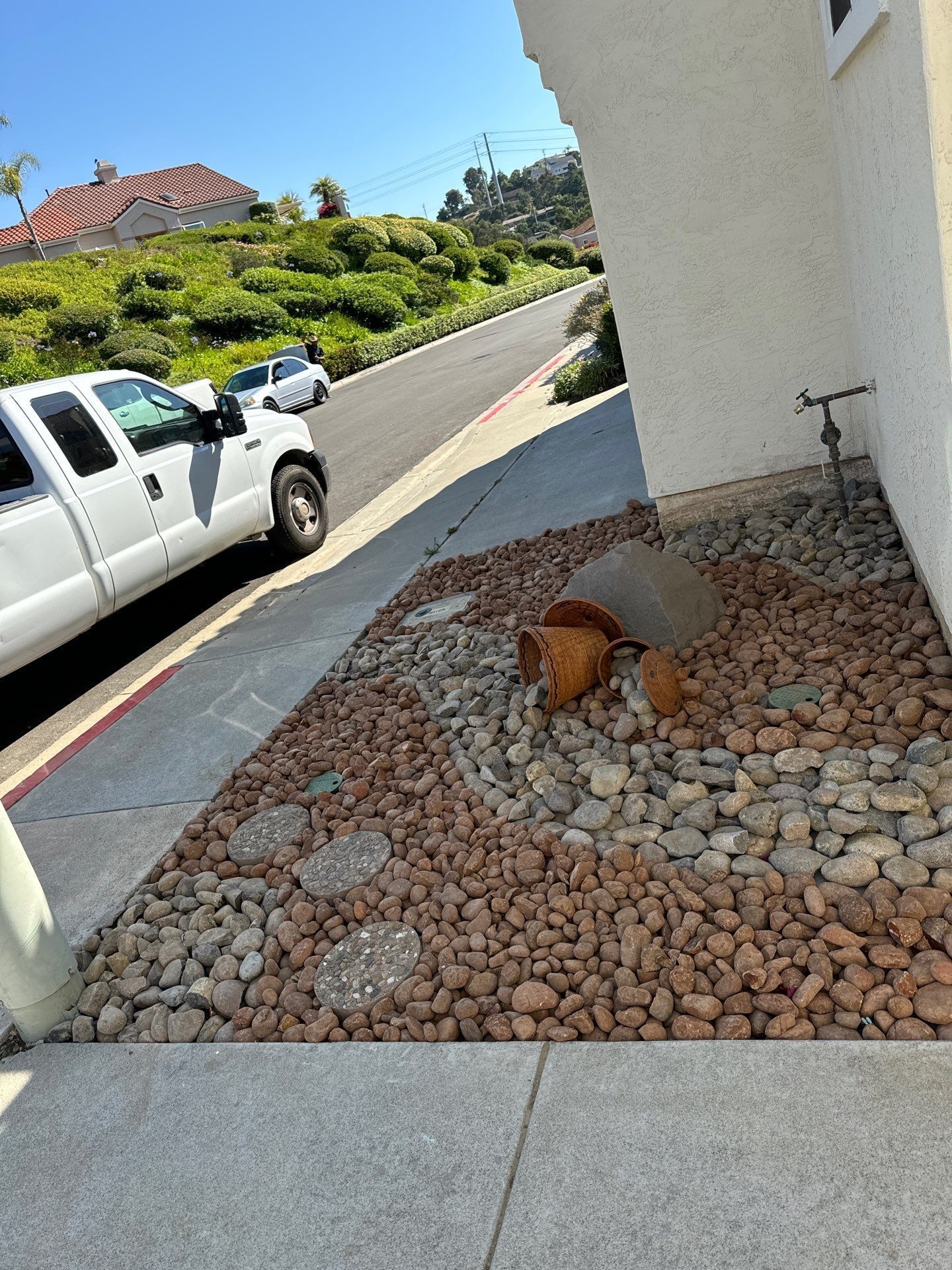 White truck parked beside sidewalk with rock garden and steps in front of a house.