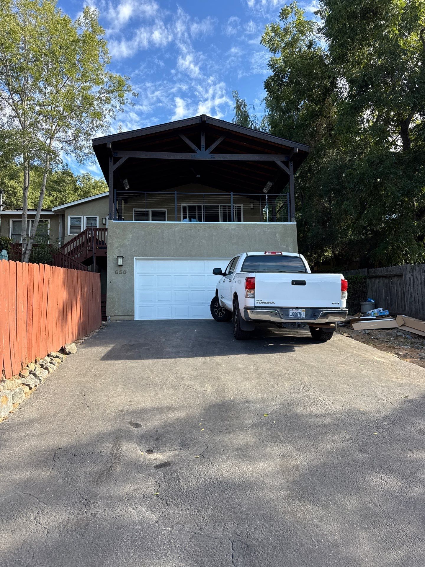 Two-story house with a white garage door, white pickup truck parked in front, and a covered porch.