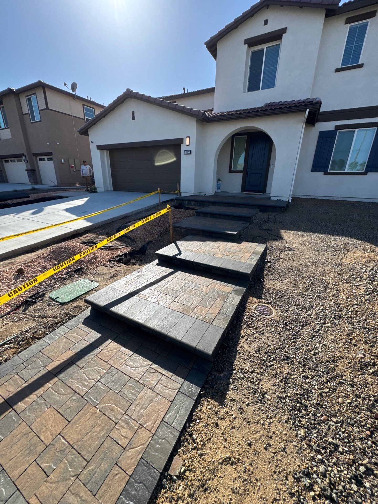 Pathway and steps leading to a house under construction; yellow caution tape in foreground.