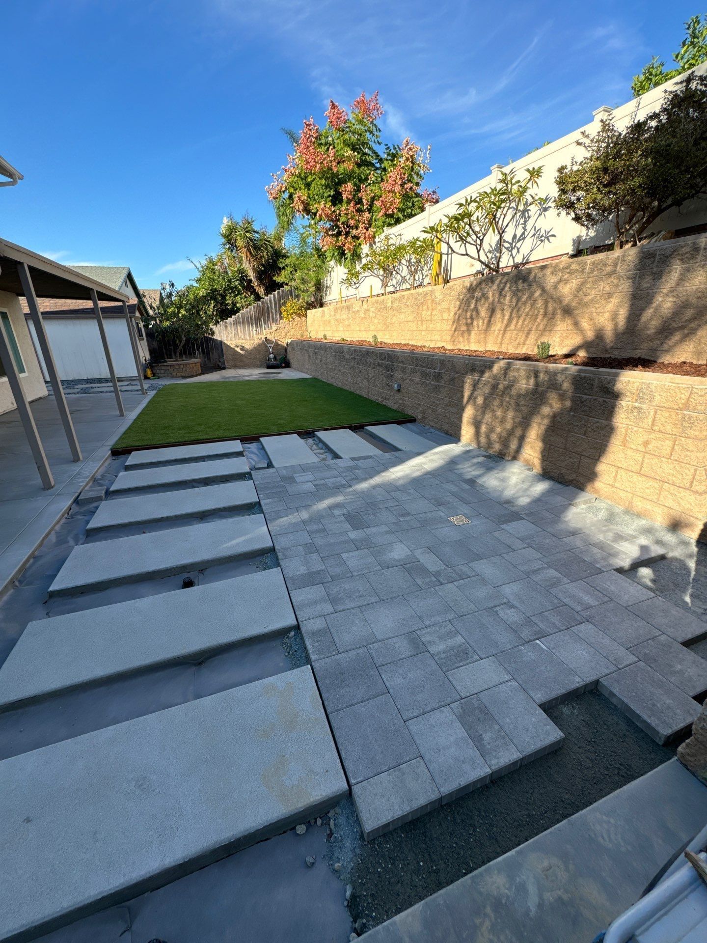 Backyard with pavers, artificial turf, and a retaining wall.