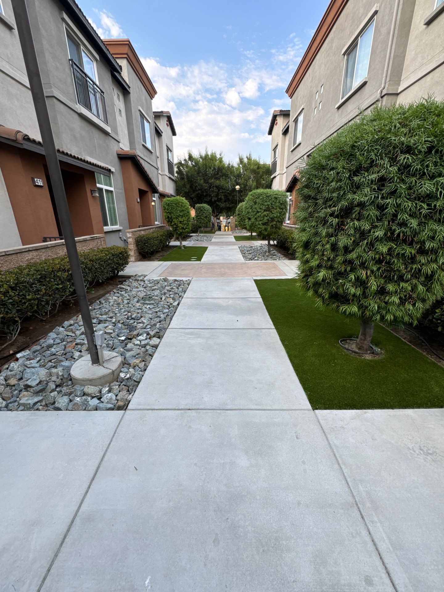 Concrete path flanked by townhouses with manicured greenery.