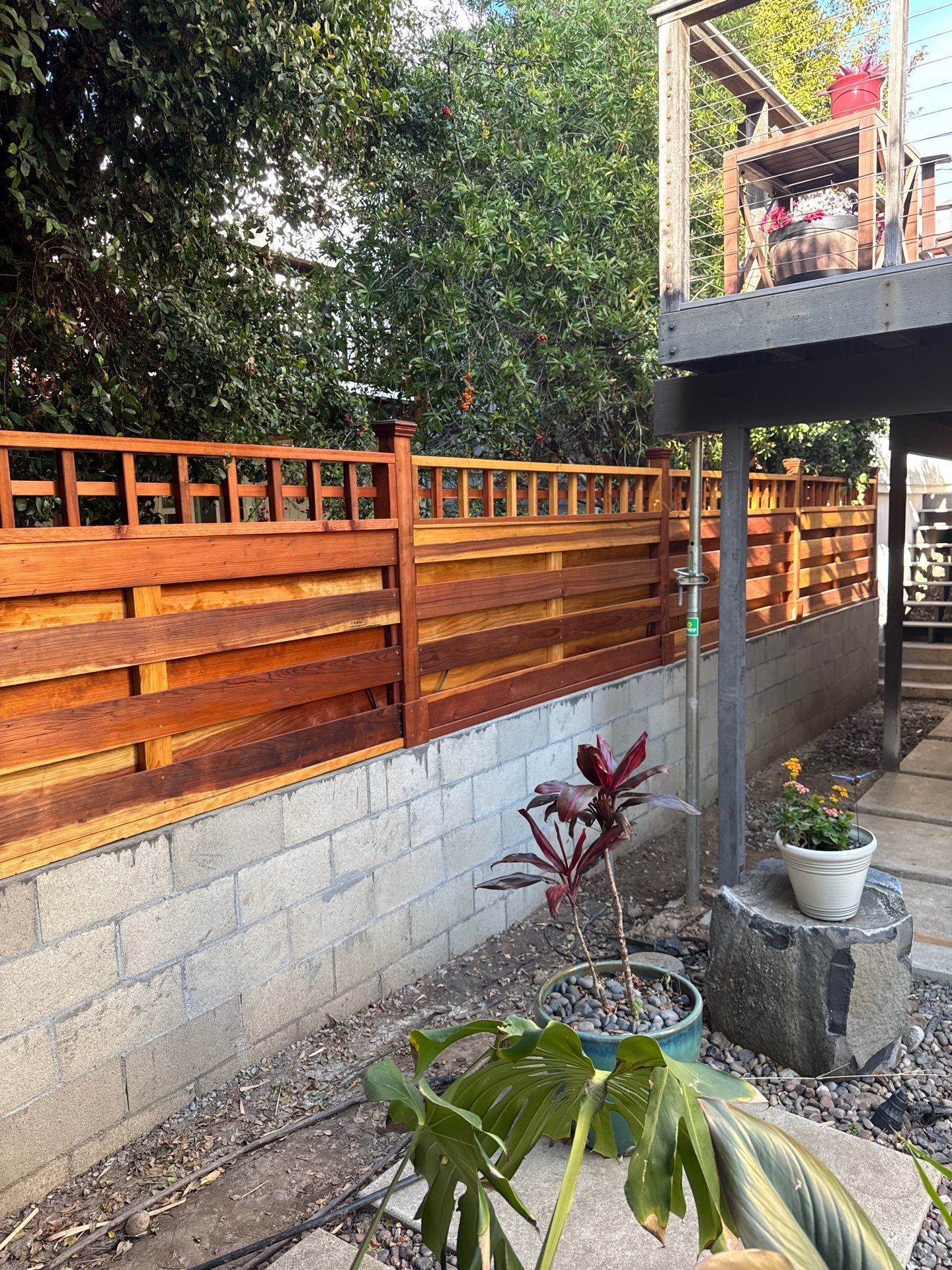 Wooden fence atop a cinder block wall, with a small garden in front.