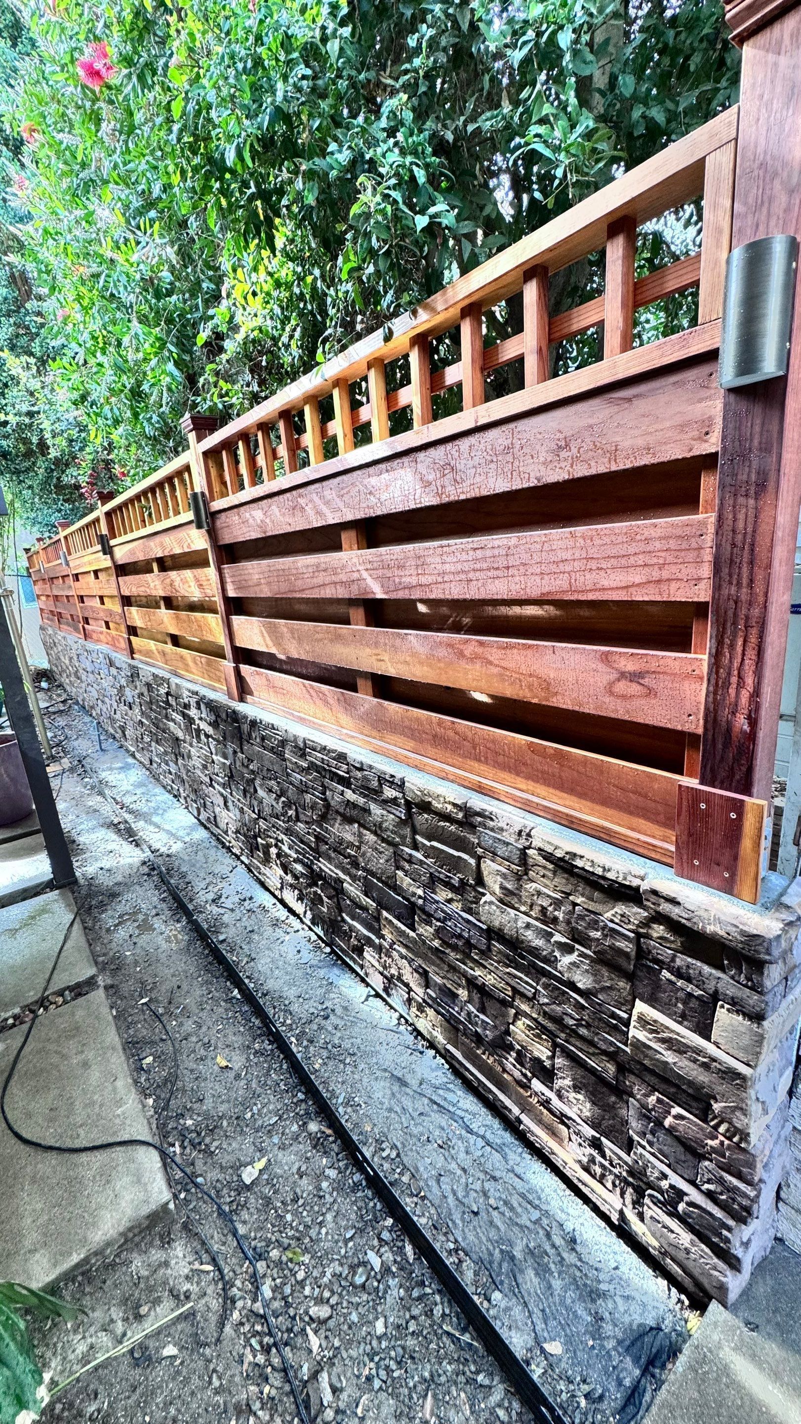 Wooden fence with a stone base in a garden setting.