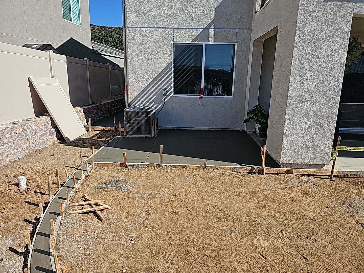 New concrete patio being constructed outside a building; wooden formwork present.