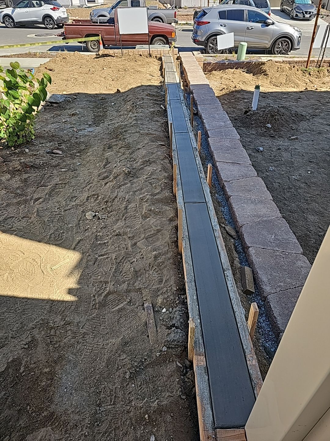 A long, narrow concrete channel bordered by brick, in front of a building, surrounded by dirt.
