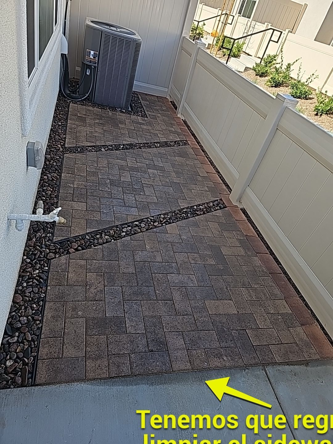 Brick patio with decorative rock border next to a fence and house wall.