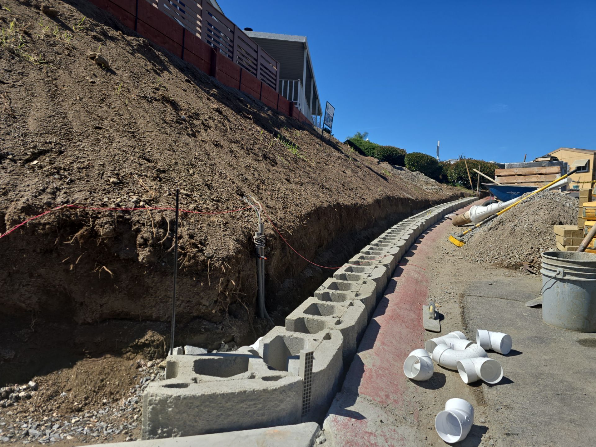 Construction site with a retaining wall being built on a hillside.