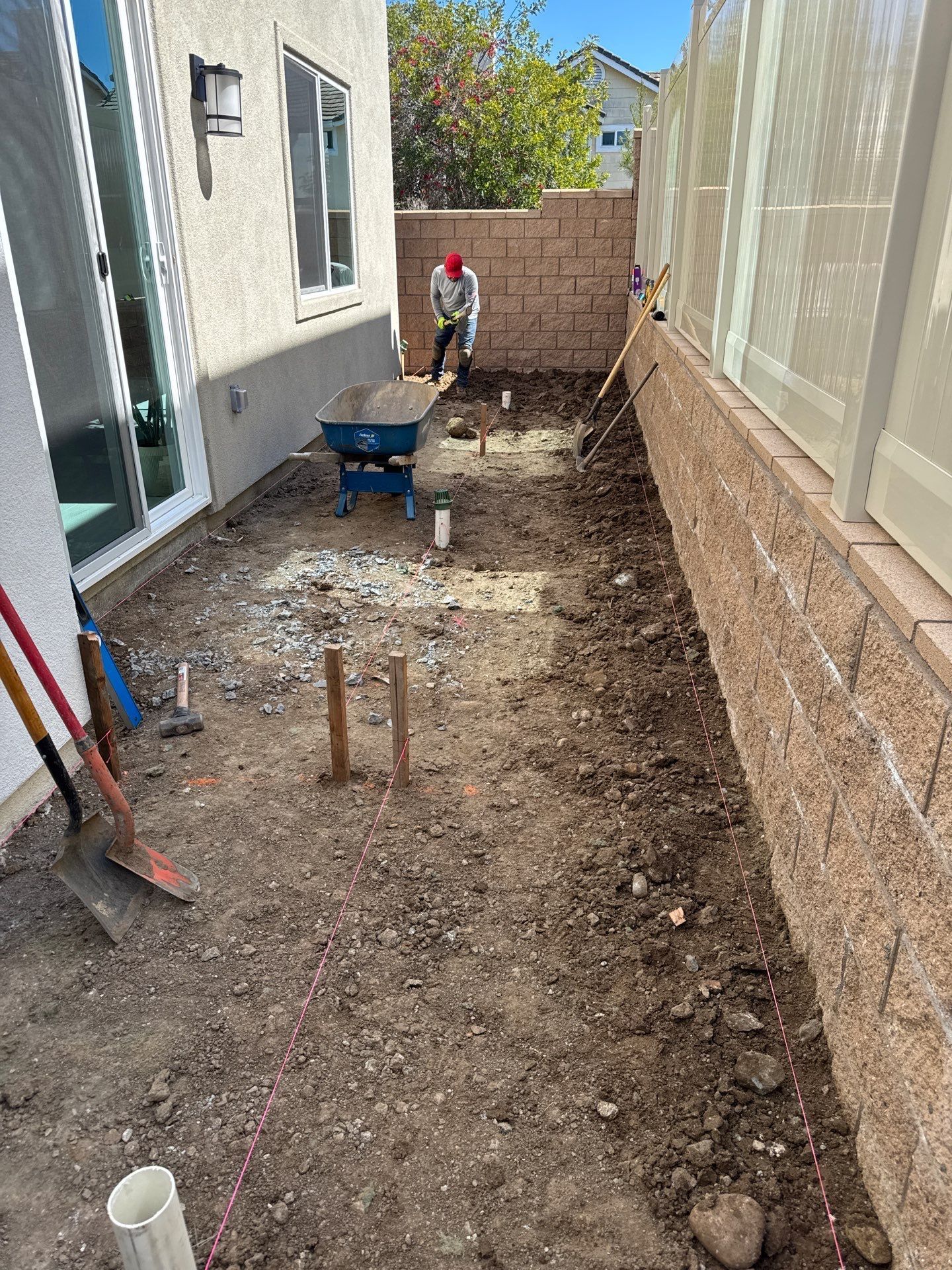 Construction worker in a yard with dirt and equipment, preparing for a project.
