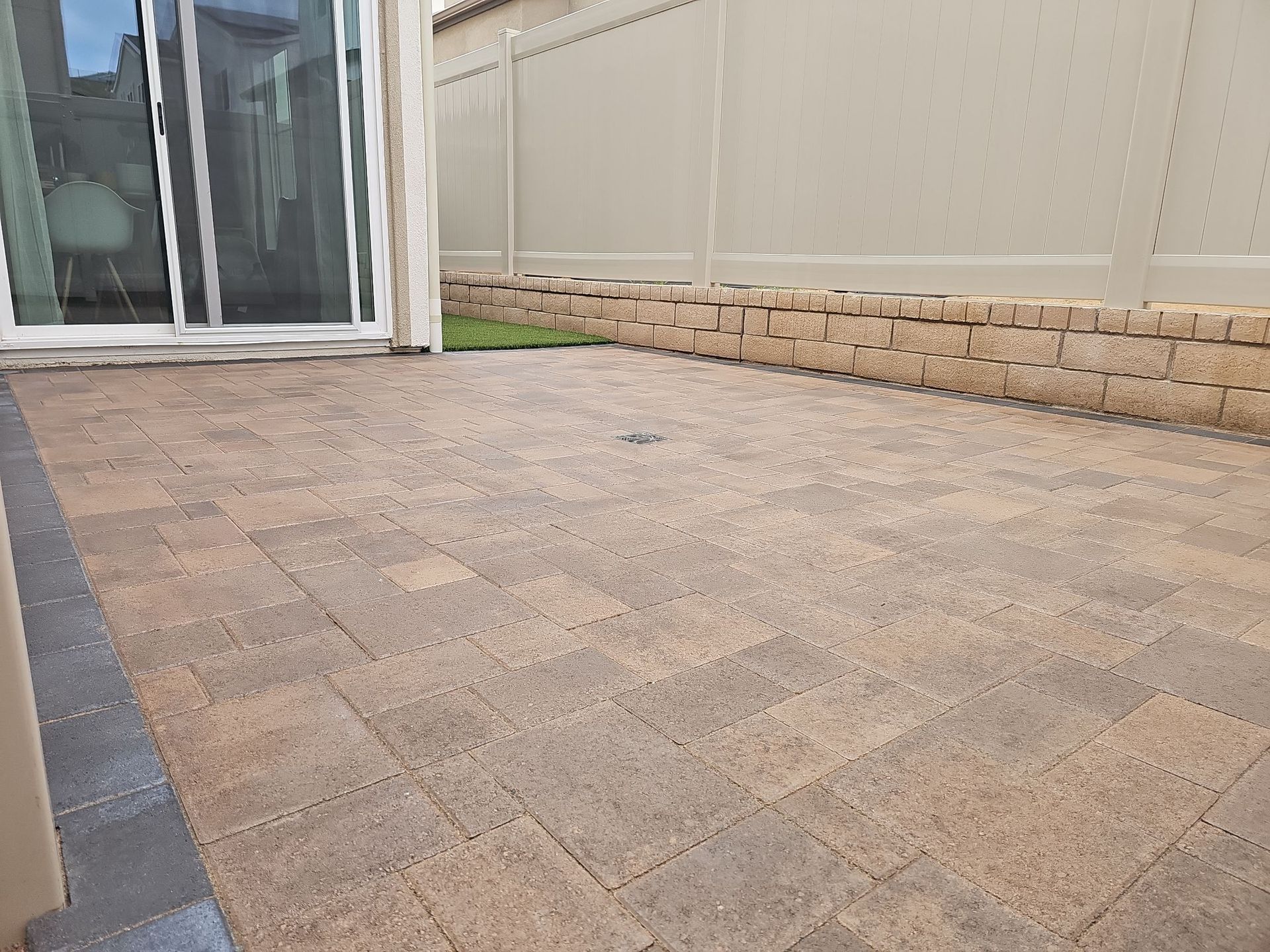 Brick patio with sliding glass door and tan fence.