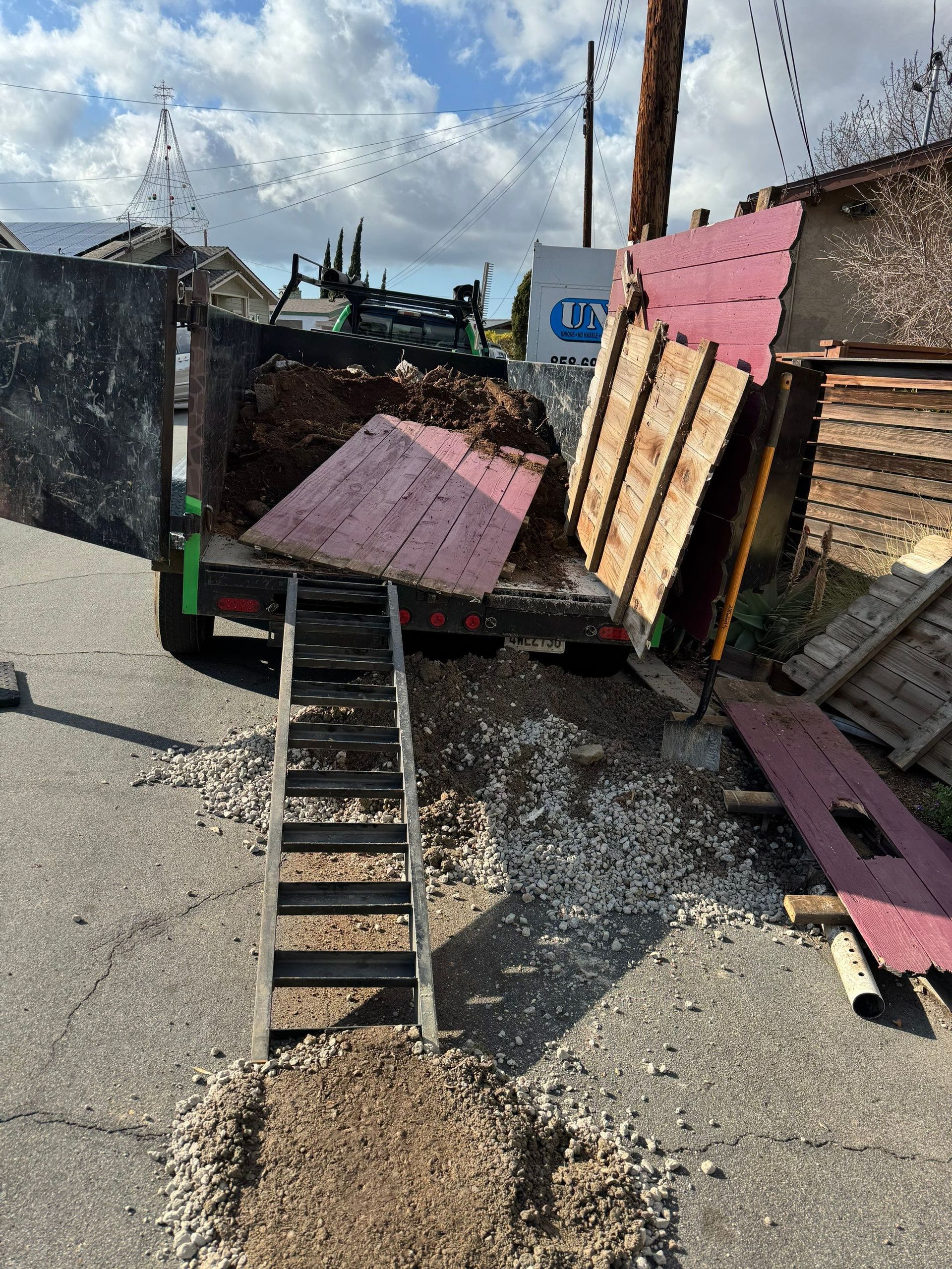 A truck is being loaded with construction debris. A ladder leads to the truck bed.