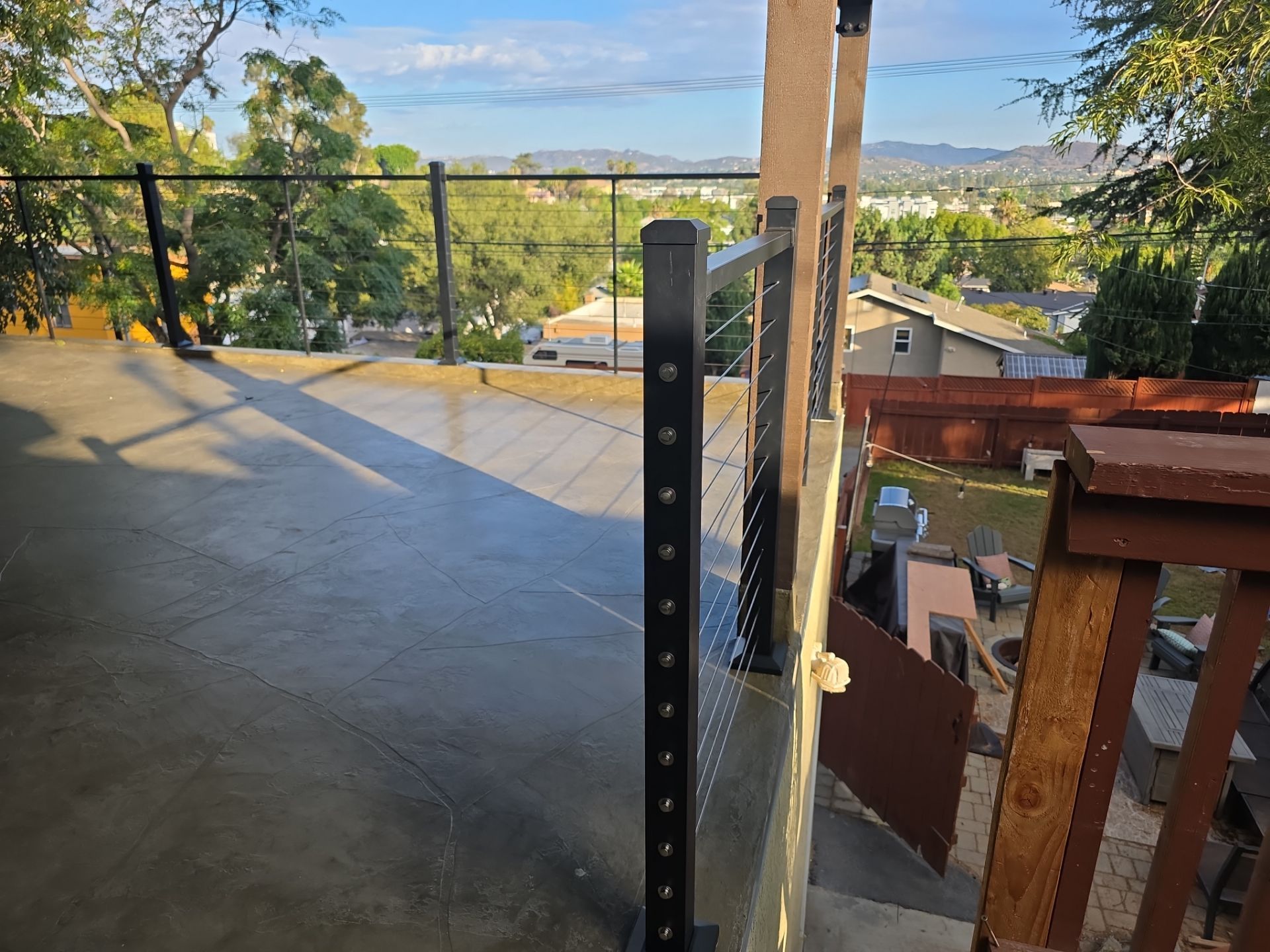 View from deck with black railing overlooking a green landscape and houses.