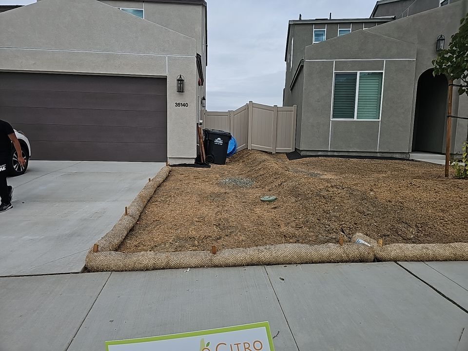 Two-story houses with a driveway and front yard covered in straw, bordered by a sidewalk.