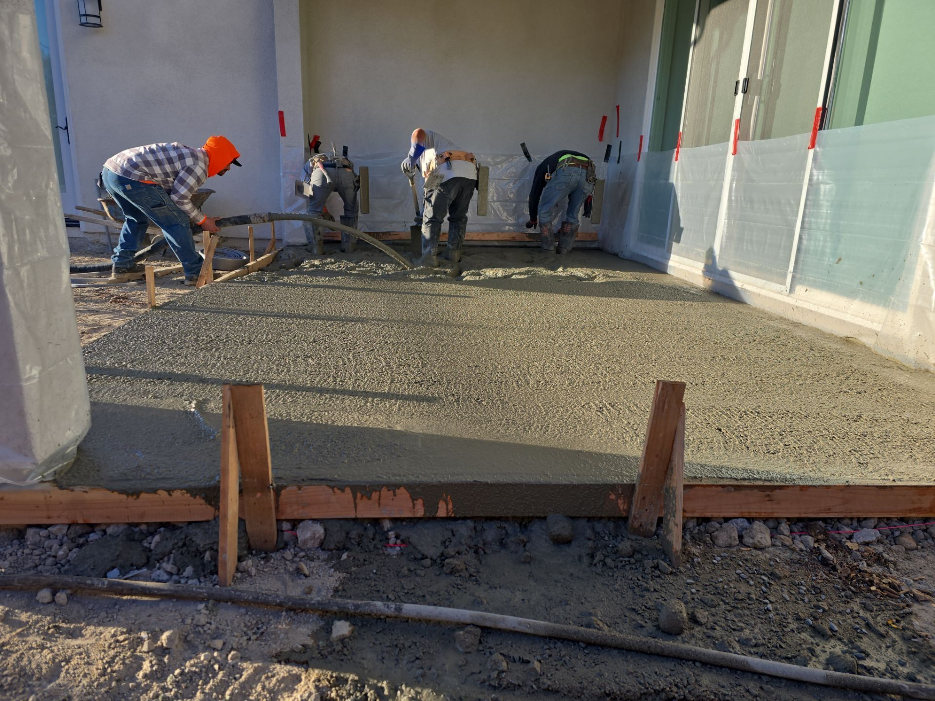 Construction workers pouring and leveling concrete slab in a building's interior.