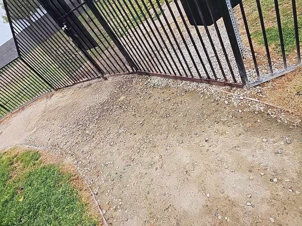 Gravel path alongside a black metal fence, curving between grass.