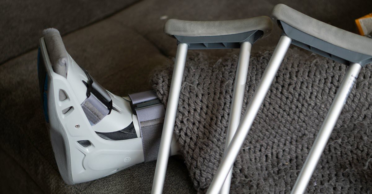 A white crutch lies beside a tipped-over white plastic chair on a carpeted floor.