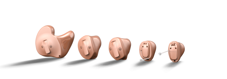 Five beige hearing aids lined up on a white background.