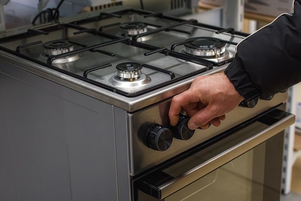 Hand turning knob on stainless steel gas stove with four burners