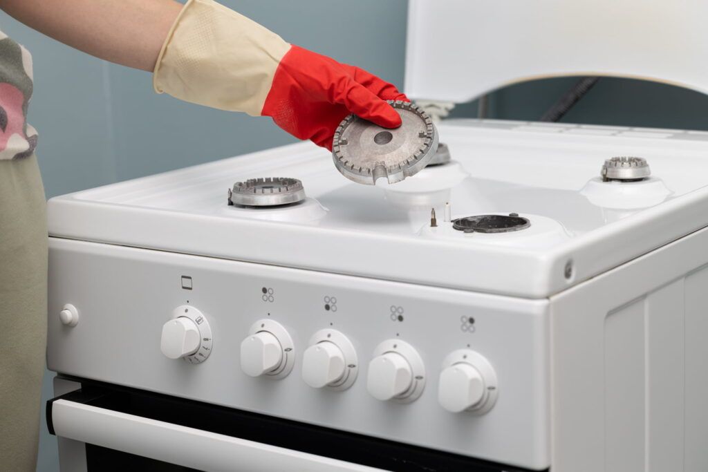 Una persona que lleva guantes rojos está limpiando una estufa de gas.