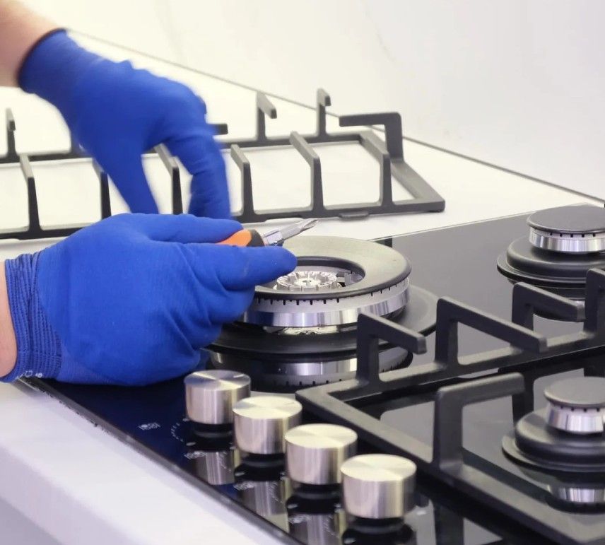 Una persona que lleva guantes azules está trabajando en una estufa de gas.