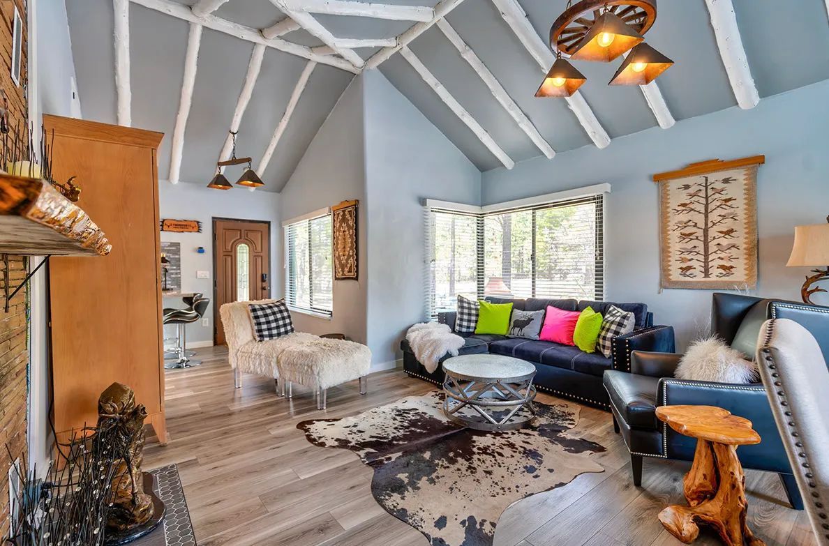 Living room with exposed beams, blue walls, a dark blue sofa, and cowhide rug.