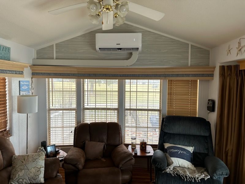 A living room with two chairs , a table , and a ceiling fan.