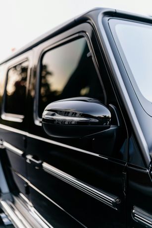 A close up of a black car 's side mirror.