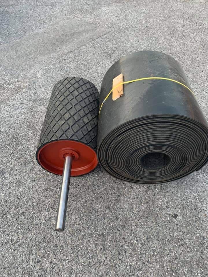 A Roll of Rubber Belt Next to A Roller on The Ground — Conveyor Maintenance Services In Ayr, QLD