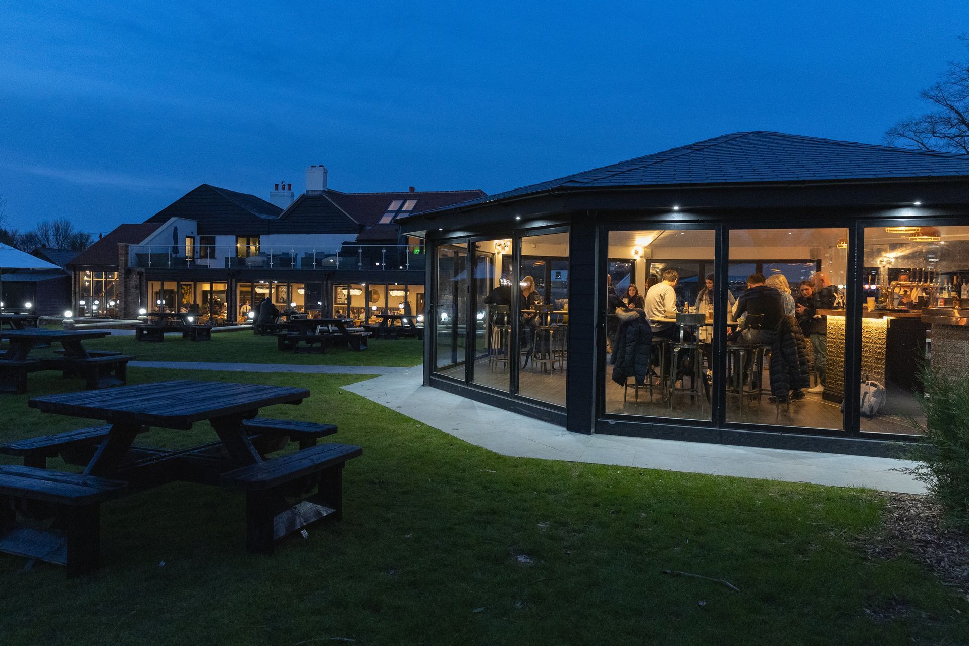 Outdoor restaurant at dusk with illuminated gazebo and patio tables.