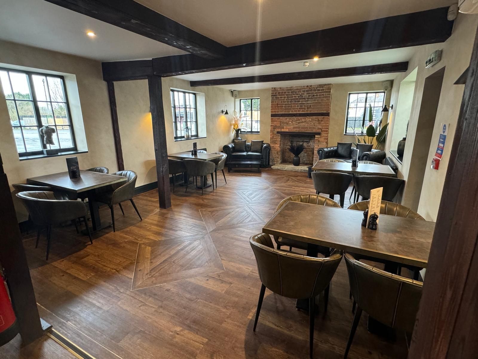 Stylish lounge area with orange seating, green walls, wooden floor, and decorative lights.