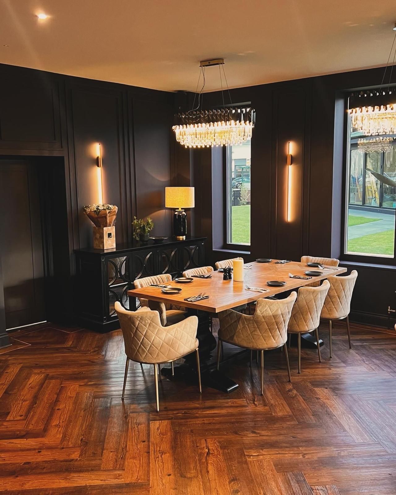 Lounge area with dark leather sofas, armchairs, fireplace, wooden beams, and hardwood floor.
