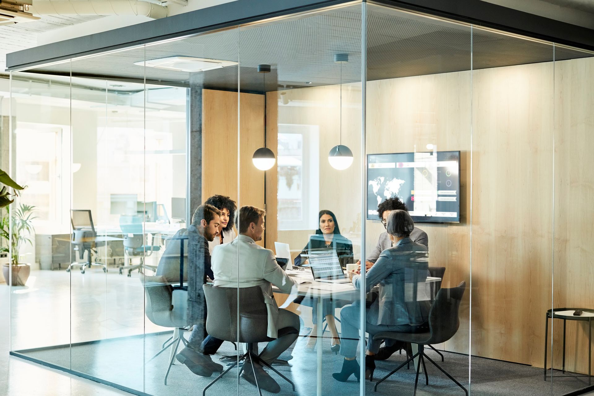 Business planning meeting in a modern glass office with diverse professionals at a round table.