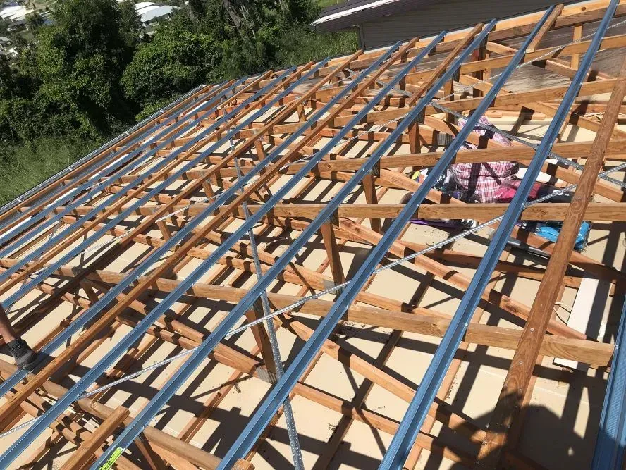 A wooden roof frame is being built on a house — Posty’s Roofing In Airlie Beach, QLD