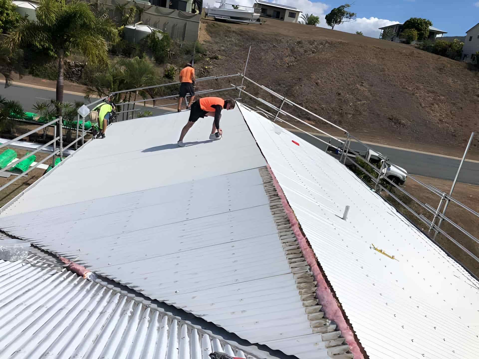 A man is working on the roof of a building— Posty’s Roofing In Airlie Beach, QLD