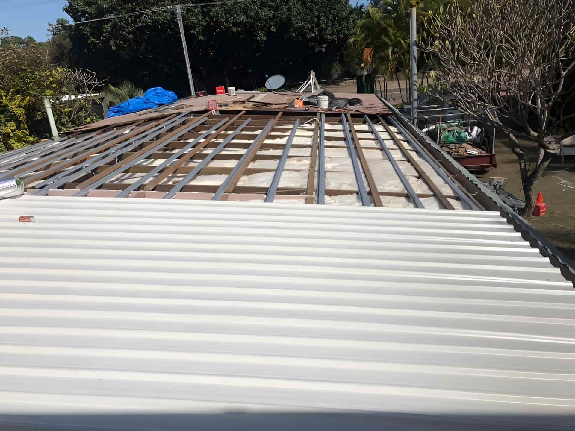 White Metal Roof Is Being Built On Top Of A Wooden Deck — Posty’s Roofing In Cannonvale, QLD