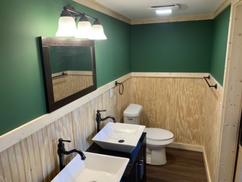 a bathroom with two sinks , a toilet , and a mirror .