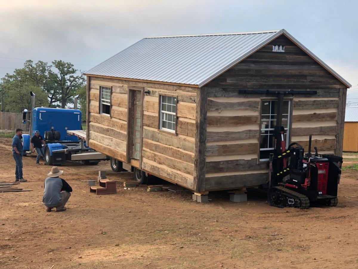 a man is standing in front of a small house that is being built.