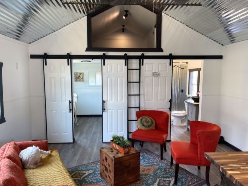 a living room with a couch , chairs , table and sliding barn doors .