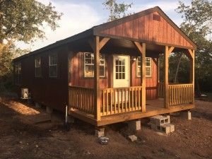 a small wooden house with a porch and a lot of windows.