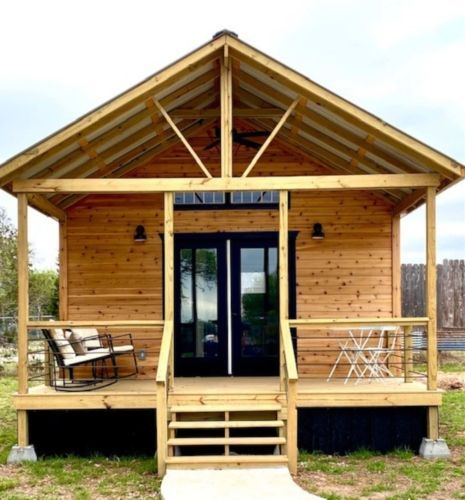 a small wooden house with a porch and rocking chairs