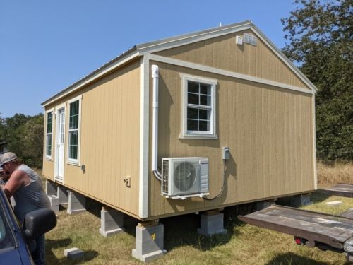 a man is standing in front of a small house that is being built.