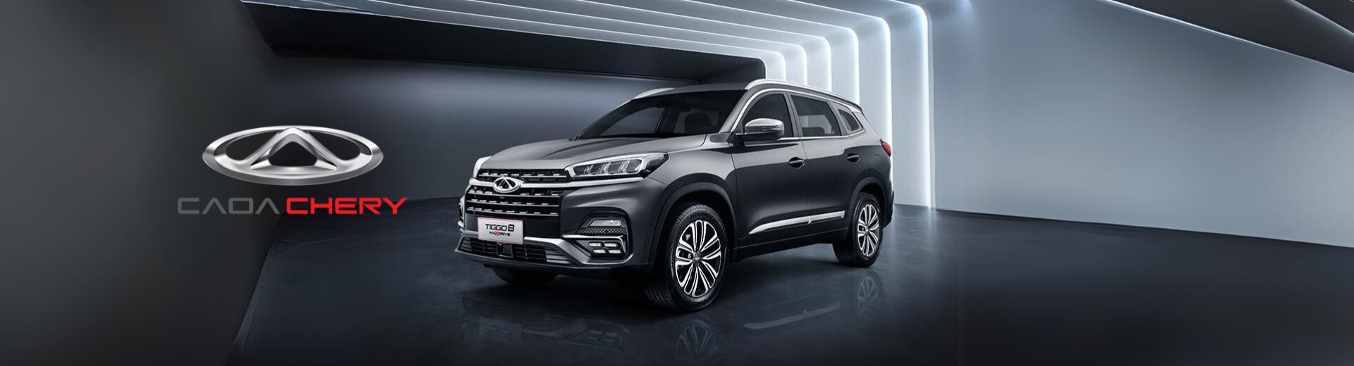 SUV Chery cinza em um showroom escuro com o logotipo da marca visível.