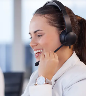 Mulher sorridente usando fone de ouvido, provavelmente funcionária de um call center, com relógio e rabo de cavalo.