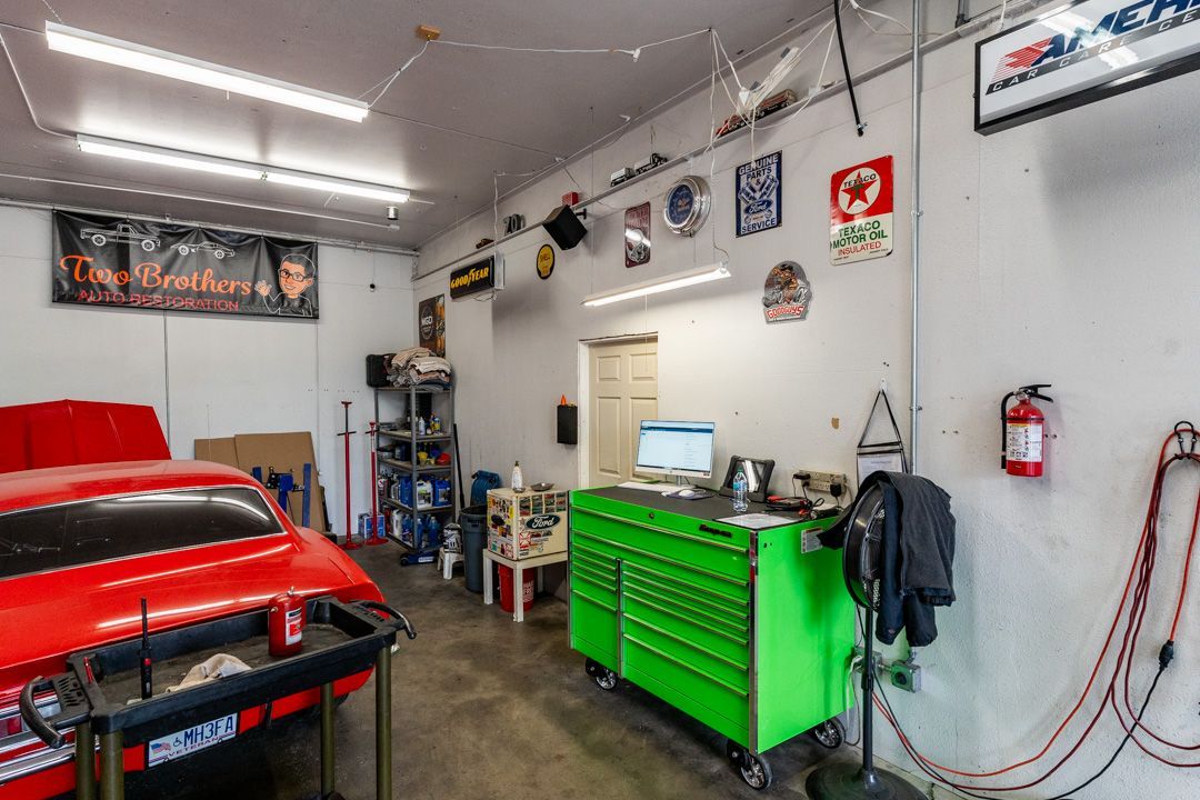 A red car is parked in a garage next to a green toolbox.